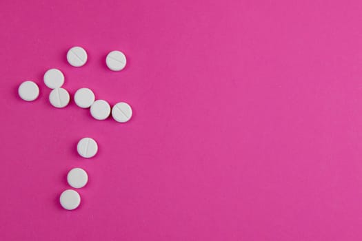 Red tablets are poured from a white plastic jar. Photo on blue background.
