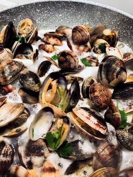 cooking clams in a stone pan using parsley and white wine. Cuisine and restaurant recipes. Shell seafood
