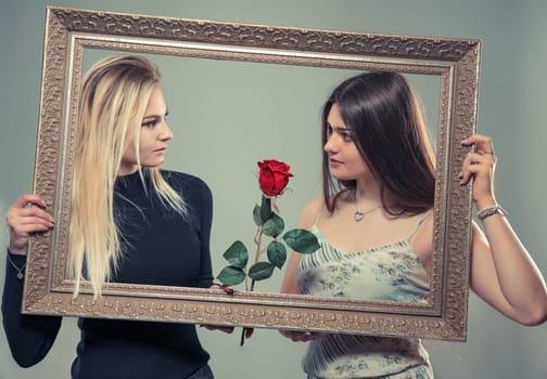 Portrait of two beautiful young women with a frame of image and roses