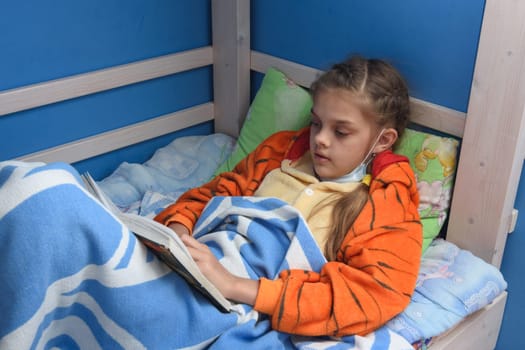 Sick girl reads a book lying in bed in bed