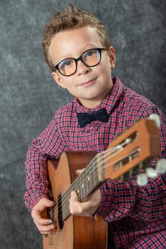 boy with a checkered shirt playing on acoustic guitar
