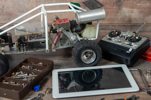 a computer tablet with RC radio control car and tools