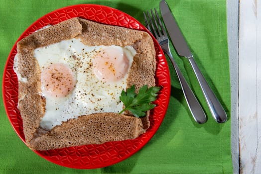homemade Breton crepe with egg in a red plate