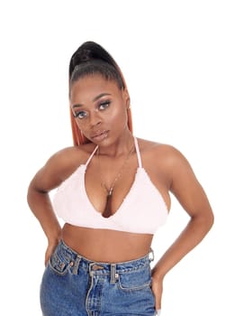 A gorgeous African American woman standing in jeans and a pink bra.in the studio looking, isolated for white background.