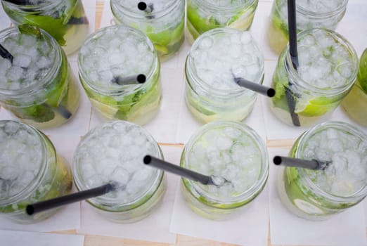 Full fresh made mojito glasses with green leaves, sugar and lime. Overhead view