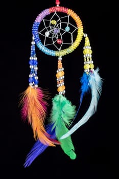 Pearl-embroidered dream catcher with colorful feathers and pearls against a black background