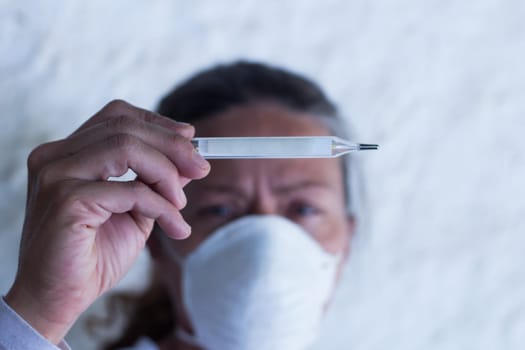adult woman with thermometer and chinstrap in prevention of influenza virus and coronavirus