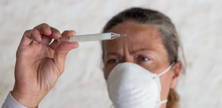 adult woman with thermometer and chinstrap in prevention of influenza virus and coronavirus