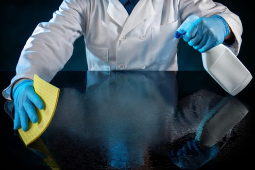 Person dressed in white uniform spraying a table with anti virus solution