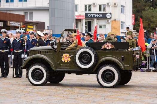 Anapa, Russia - May 9, 2019: A car with veterans and children awaits the start of the Victory Parade on Anapa Theater Square at Victory Day celebration