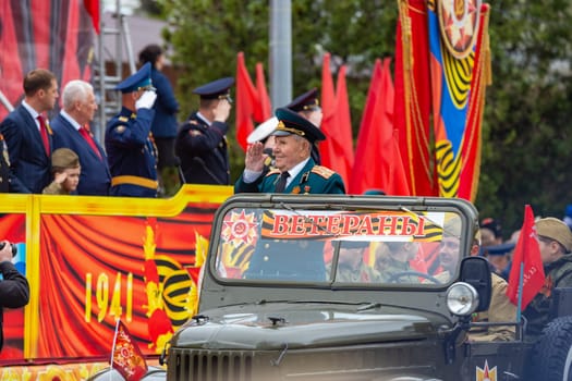 Anapa, Russia - May 9, 2019: Veteran in a military old car greets honorary figures in the theater square of Anapa on the celebration of Victory Day