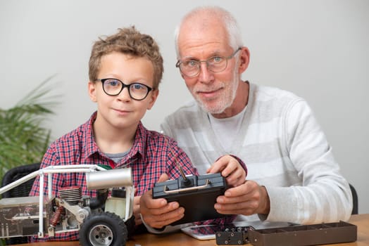grandpa and son little boy repairing  model radio-controlled car at home