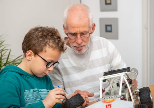 grandpa and son little boy repairing a  model radio-controlled car at home