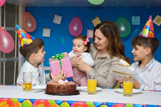 Two boys congratulate mom, mom holds in her arms a six-month-old baby