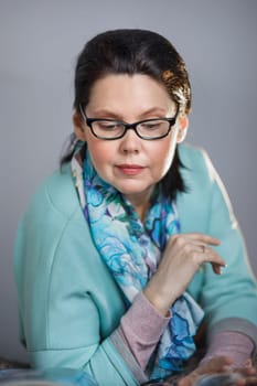 Middle-aged brunette woman reading a magazine with interest.