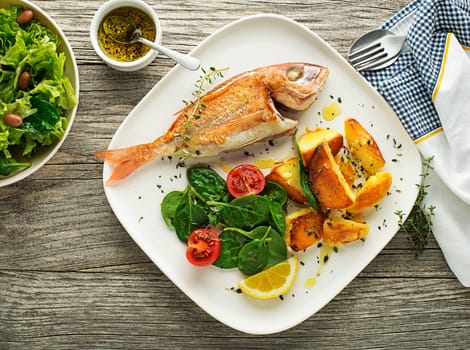 Delicious grilled fish meat with spinach and potatoes on vintage background. Healthy diet meal