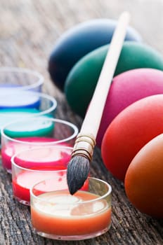 Coloring Easter eggs with a brush and paint on wooden table