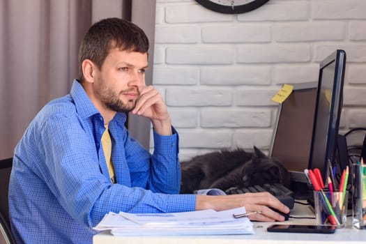 Freelancer thoughtfully looks out the window, sitting at his workplace