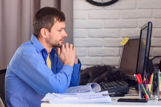 Worker at a remote work looks thoughtfully at a monitor screen