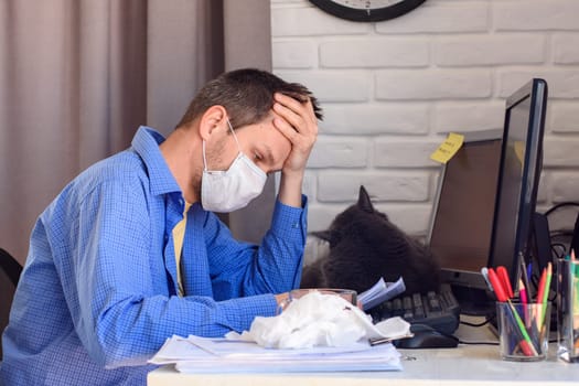 A man in a protective medical mask sits at a computer in a home stop and reads documents
