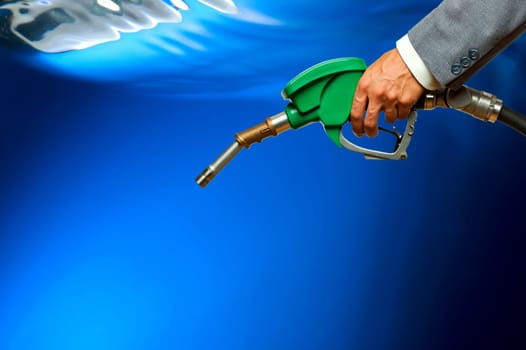 Refueling hose on blue background. Holding green color fuel gasoline dispenser background. Petrol price goes down after pandemic coronavirus. low price of fuel.