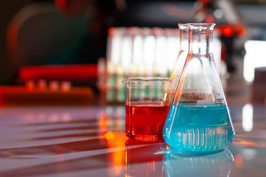 Illuminated laboratory flask filed with colorful chemical solutions with shadows on the table. Laboratory, science, reaserch, chemistry... consept.