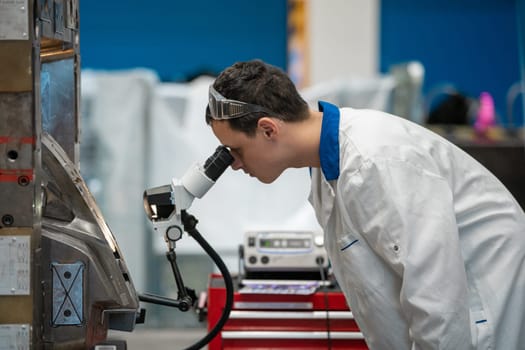 the engineer checks the correct setting of the metal mold for castings in the factory using a microscope.
