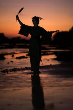Silhouette of Japanese Geisha in kimono with fan at sunrise