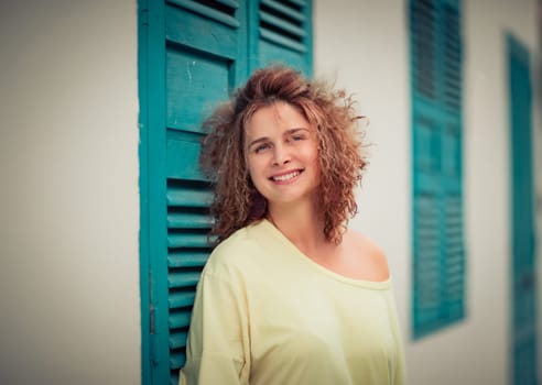 Outdoor portrait of a beautiful woman next to shutter window