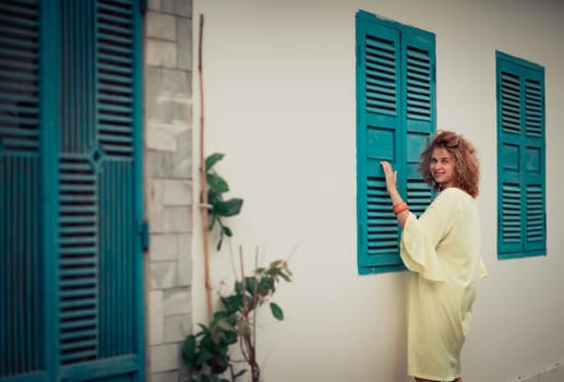 Outdoor portrait of a beautiful woman next to shutter window