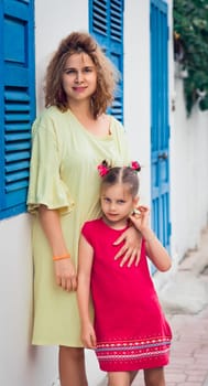 Mother and daughter next to shutter window in a street