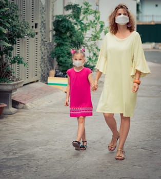 Woman and daughter wearing facial disposable mask to avoid viral infection. Coronavirus protection