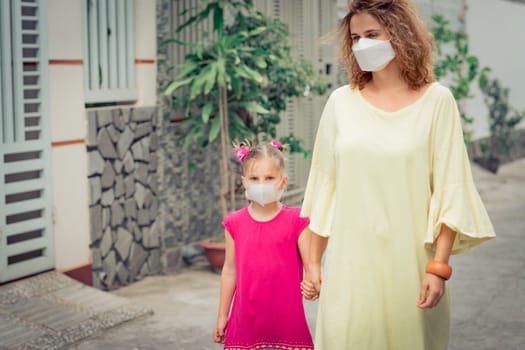 Woman and daughter wearing facial disposable mask to avoid viral infection. Coronavirus protection