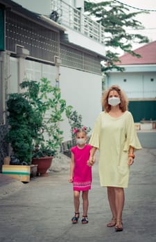 Woman and daughter wearing facial disposable mask to avoid viral infection. Coronavirus protection
