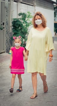 Woman and daughter wearing facial disposable mask to avoid viral infection. Coronavirus protection