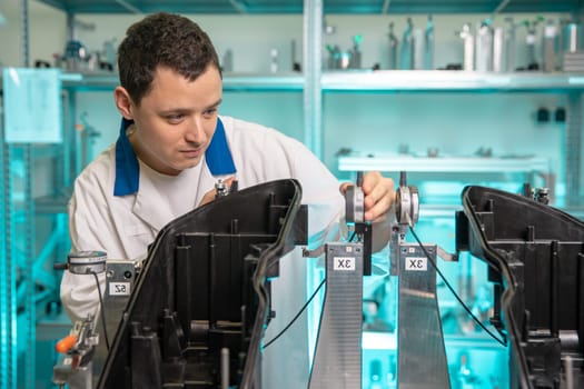 engineer measures plastic components for the production of lights for the automotive industry in a factory on a digital 3D machine.