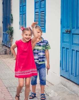 Kids walking by the street next to shutter blue window