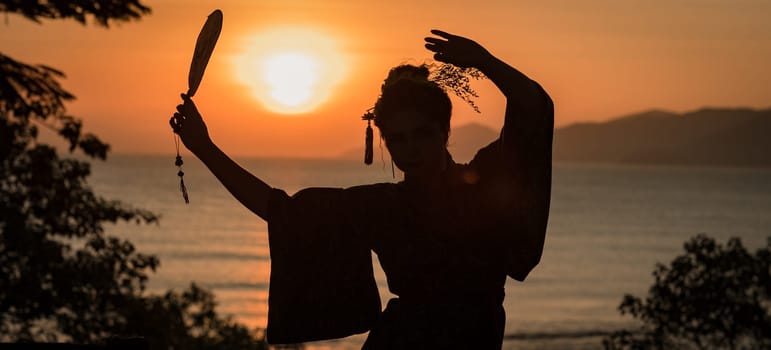 Silhouette of Japanese Geisha in kimono with fan at sunrise