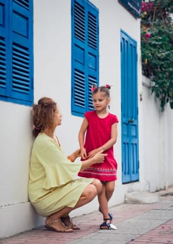 Mother and daughter next to shutter window in a street