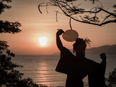 Silhouette of Japanese Geisha in kimono with fan at sunrise