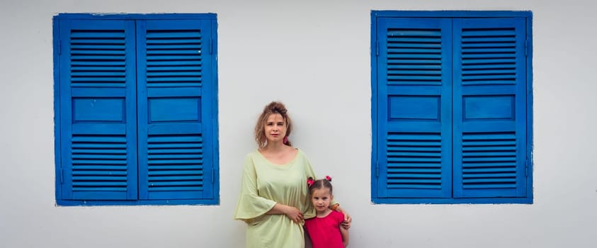 Mother and daughter next to shutter window in a street