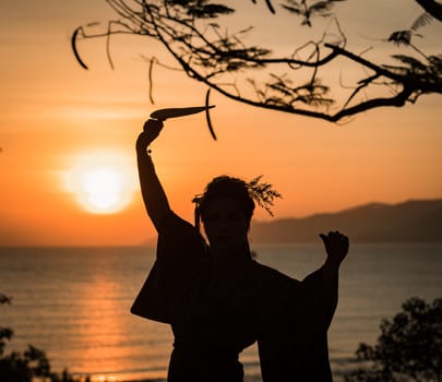 Silhouette of Japanese Geisha in kimono with fan at sunrise
