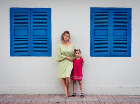 Mother and daughter next to shutter window in a street