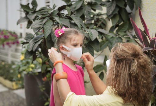 Woman and daughter wearing facial disposable mask to avoid viral infection. Coronavirus protection