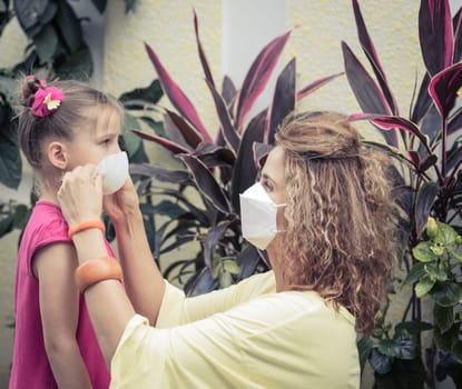 Woman and daughter wearing facial disposable mask to avoid viral infection. Coronavirus protection