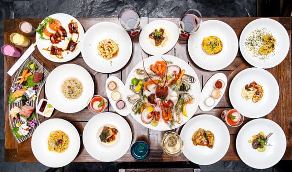 Table top view premium variety of international food in restaurant of lobster shrimp steak beef lamb pasta spaghetti risotto rice sushi sashimi and wine using for buffet food drink background.