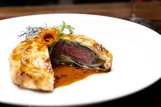 Roasted Beef Wellington with gravy brown savory sauce, international gourmet cuisine of stuff beef meat in baked bread puff. Unising for recipe menu pf food and drink industry.