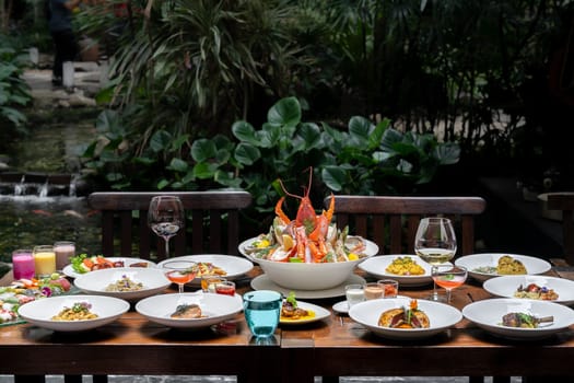 Side view premium variety of international food in garden of restaurant of lobster shrimp steak beef lamb pasta spaghetti risotto rice sushi sashimi and wine using for buffet food drink background.