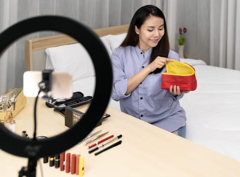 Young beautiful Asian woman beauty vlogger blogger recording live make up tutorial share on social media using mobile phone. Using for vlog social media influencer concept.
