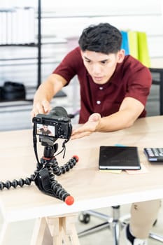 Young asian male blogger setting up camera for recording live vlog video tutorial session at home. IT blogging or vlogging, social media hobby broadcasting, or online learning course concept.
